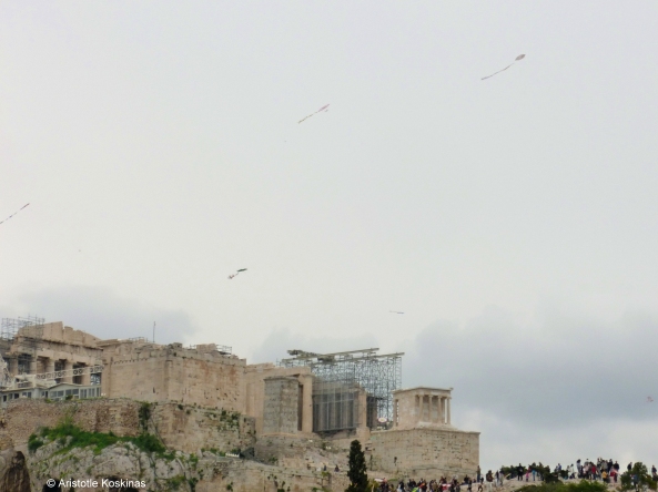 Χαρταετοί πετούν πάνω από την Ακρόπολη, εδώ από ΒΔ. Χαριτωμένη λεπτομέρειια: ένας χαρταετός φαίνεται να έχει πέσει δίπλα στο Ναό της Αθηνάς Νίκης, μπροστά από τις σκαλωσιές.
